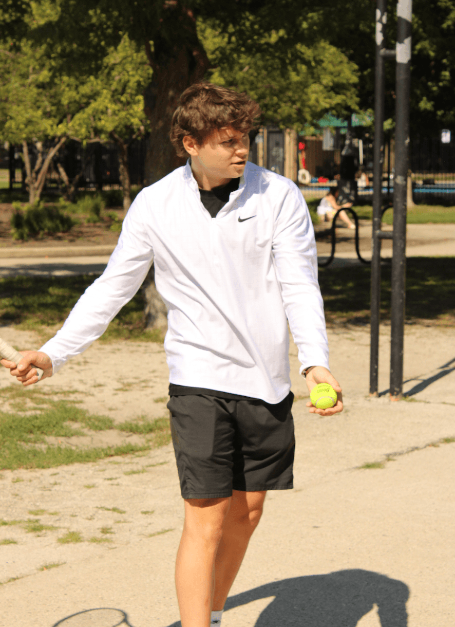 A DePaul tennis player demonstrating footwork during a coaching session in a Chicago park